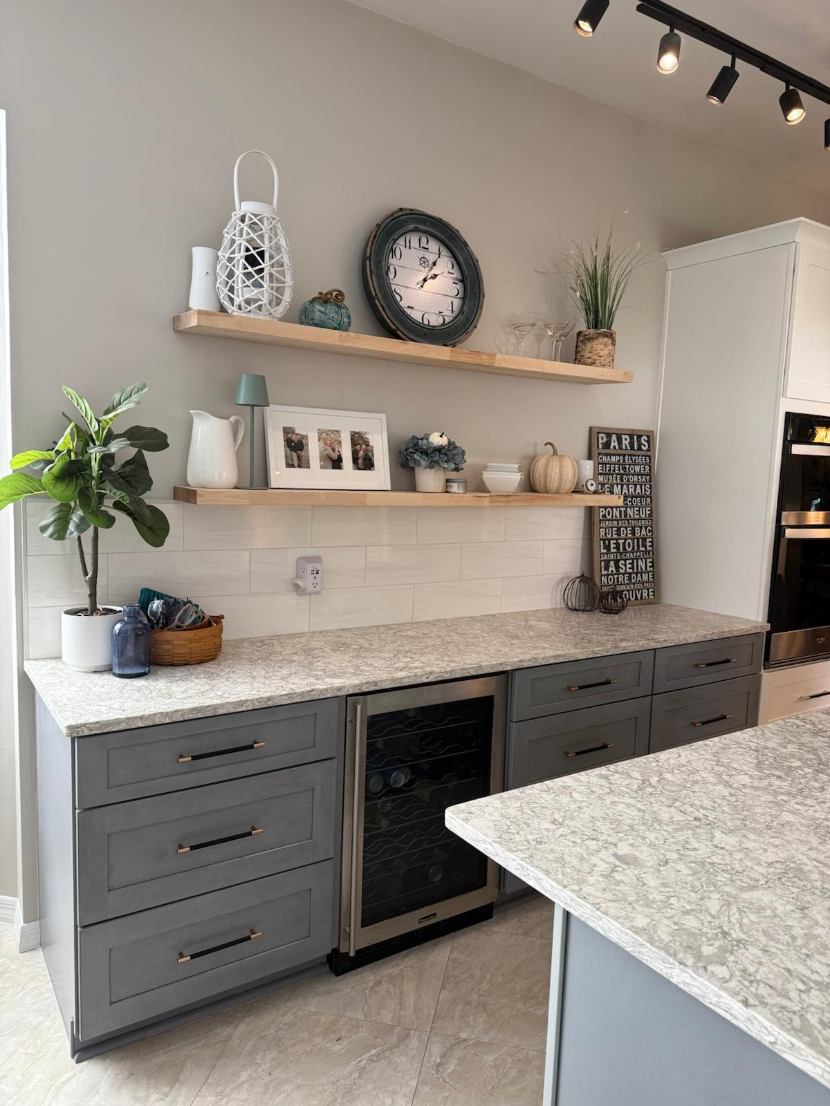 Remodeled kitchen with gray cabinetry, open wood shelving, and stone countertops